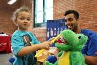 A Penn Dental Student teaches a toddler how to brush teeth at the EHS Health Fair